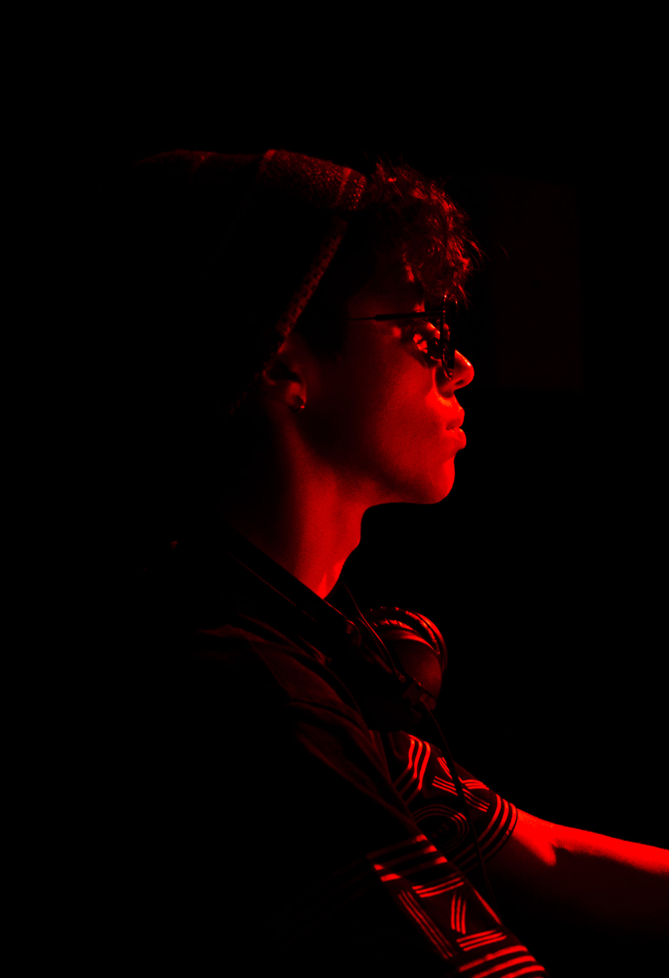 Red-lit profile portrait of JACÓSTA in the booth